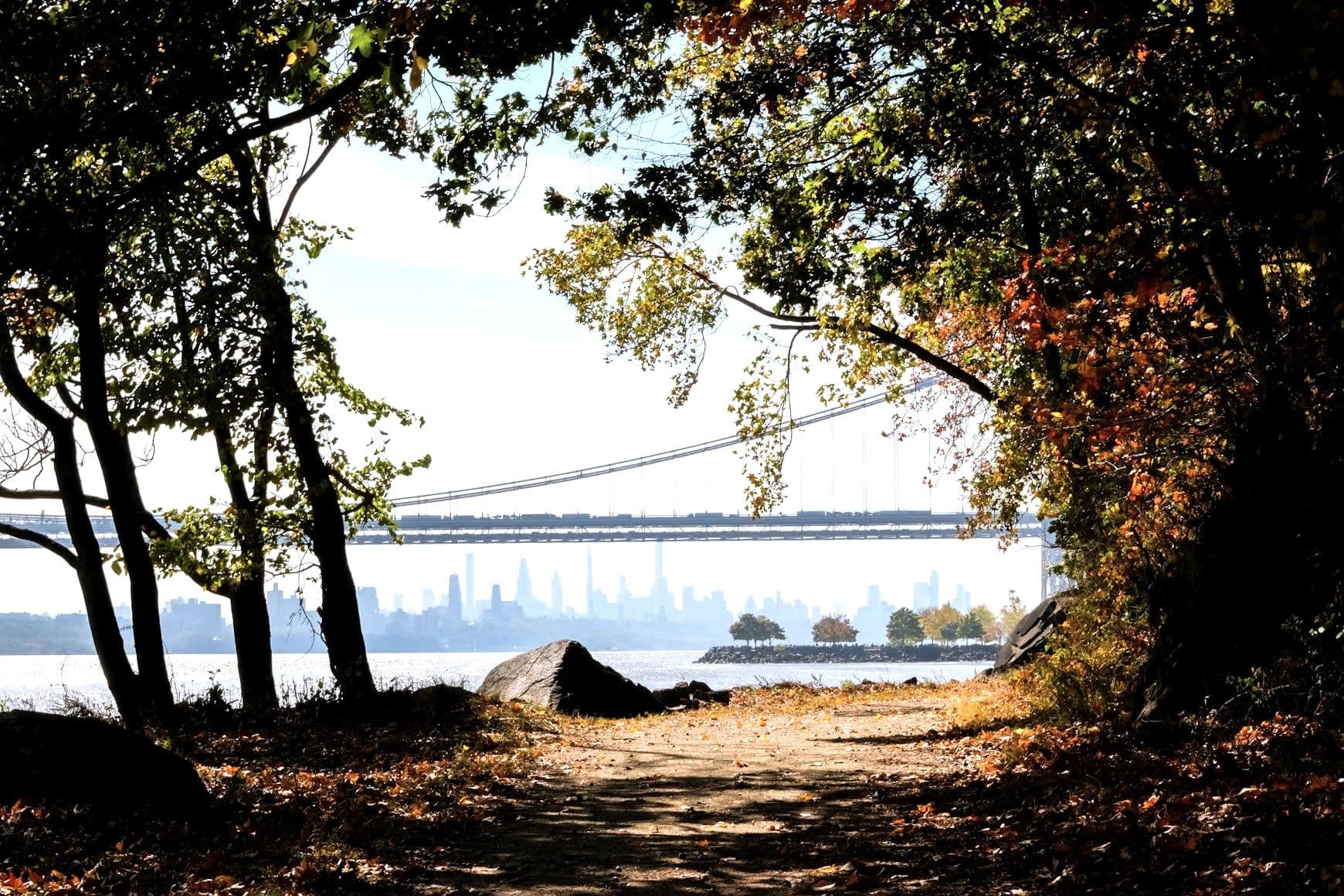 A wooded path on the New Jersey Palisades in autumn, looking across the Hudson to the Manhattan skyline and the George Washington Bridge